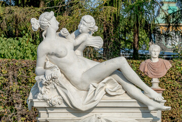 Old statue of a sensual Renaissance era beautiful woman after bathing with an angel in a city park...