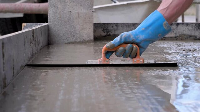 Person with blue gloves paving the cement flat.