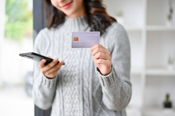 cropped image, Beautiful young Asian woman holding er smartphone and a credit card.