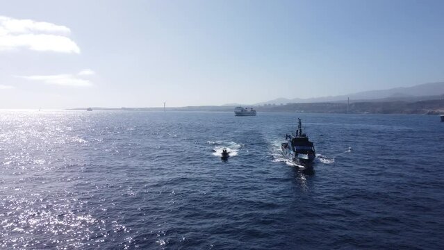 Aerial shot towards the prow of the police patrol next to one of the boats it owns. Customs patrol against drug trafficking.