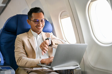 Successful Asian businessman checking his watch for the arrival time, on the flight for business trip.