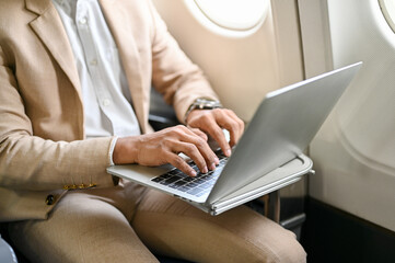 A businessman using a laptop, managing his business tasks during the flight. cropped image