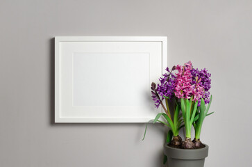 Blank landscape frame mockup on grey wall with hyacinth flowers in pot