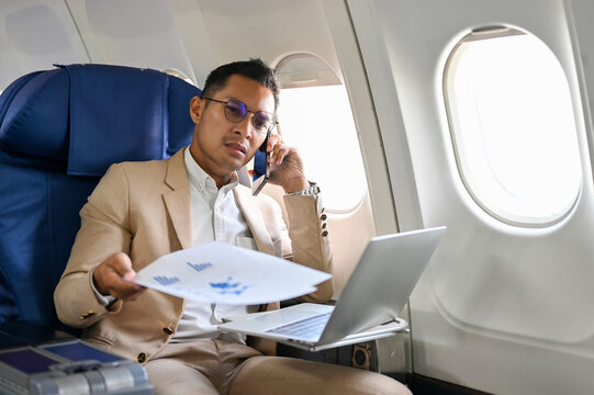 Stressed Asian businessman is having a serious conversation on the phone during the flight - Powered by Adobe