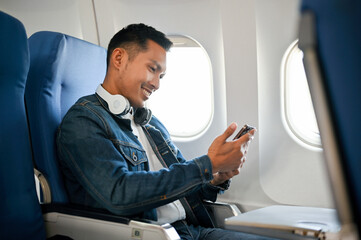 side view, Asian male passenger using his smartphone during the flight. © bongkarn