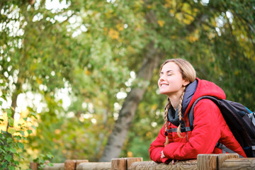 Naklejka na ściany i meble Smiling young female trekker breathing fresh air in the forest.