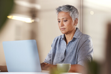 Office, coffee and mature woman with laptop typing idea for creative startup business or report at desk. Senior freelance worker, designer or writer, thinking and working on ideas in modern office