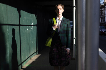 fashion portrait of non-binary person in city with dramatic sunlight
