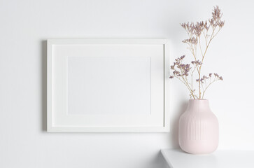 Landscape blank frame mockup on wall with dry flowers in vase