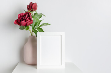Blank portrait frame mockup with fresh peony flowers in vase, frame mockup for artwork or photo