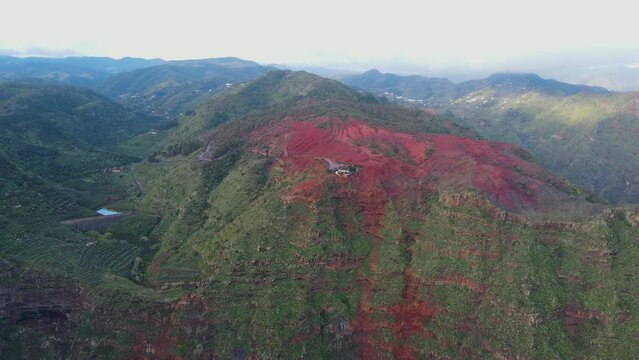Aerial view of stunning viewpoint Mirador de Abrante with glass observation balcony above Agulo village in La Gomera island at sunrise. Restaurant on red clay.