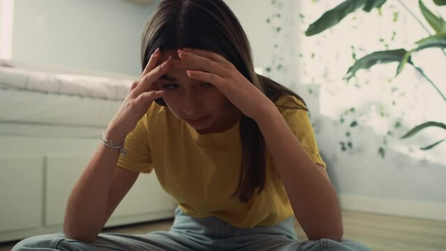 Zoom out of caucasian teenage girl sitting on floor with head in hands and trying to learn. Shot with RED helium camera in 8K.   