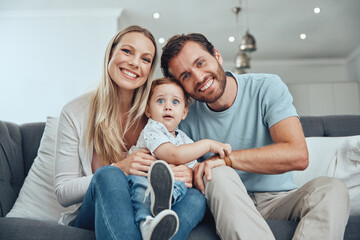 Happy, smile and portrait of a family on a sofa relaxing, bonding and holding their child at their home. Mother, father and baby boy sitting in the living room together with love, care and happiness.