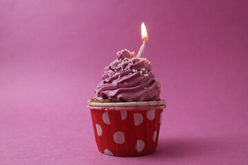 cake cupcake basket with a cap of cream pink lilac with a burned candle. Anniversary 1 year holiday birthday with space for text pink background