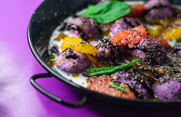 Breakfast in black plate on purple background with lazy cheesecakes currant, strawberry, blueberry, chia, mint and coconut sauce.