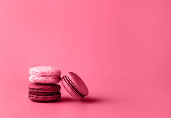 Obraz na płótnie Canvas Three macaroons in stack toned in trendy magenta color of year 2023. Food concept. Copy space. Close-up.