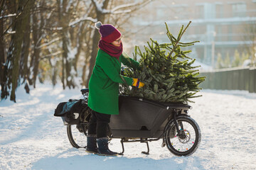 Woman transporting Christmas tree on cargo bike
