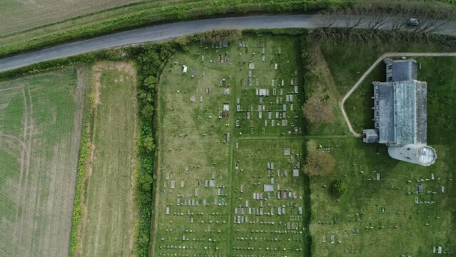 Topdown Aerial Drone Shot Flying Over Old Medieval 11th Century Round Tower Church with Graveyard on Cloudy Day in North Norfolk UK