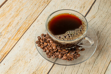 hot coffee and coffee beans on wooden table with full cup. text area