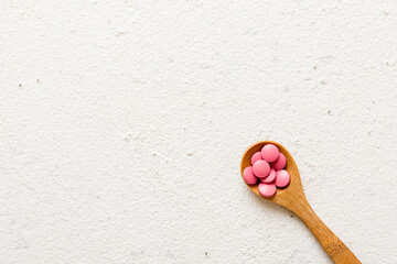 Vitamin capsules in a spoon on a colored background. Pills served as a healthy meal. Red soft gel vitamin supplement capsules on spoon