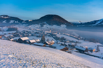 Panorama mit dem Dorf Hittisau im Bregenzerwald im ersten Schnee. Winter in Vorarlberg, mit Bergdorf, Wiesen, Wälder und Berge im Hintergrund