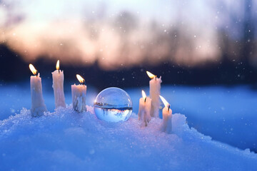 magic quartz ball and candles on snow, winter natural blurred background. christmas and new year...