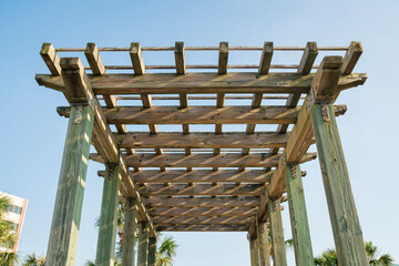 Obraz premium View of a wooden grid pergola roof from below against the sky at Destin, Florida