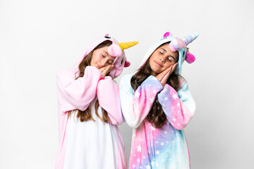 Friends girls with unicorn pajamas over isolated white background making sleep gesture in dorable expression