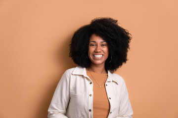 happy black young woman smiling and standing wearing white jacket in beige background. portrait,...