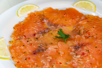 Smoked salmon carpaccio with garnish served on a white plate
