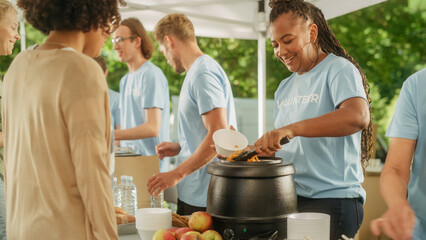 Team of Young Volunteers Helping in a Local Community Food Bank, Handing Out Free Food to Low-Income People in a Park on a Sunny Day. Charity Workers Work in Humanitarian Aid Donation Center.
