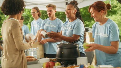 Humanitarian Aid Concept: Volunteers Preparing Free Food and Feeding Local Community that is in...