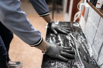 A tattoo artist is preparing his work table with plastic film