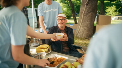Happy Middle Aged Man with Disabilities Using Wheelchair Receiving a Charity Meal from a Humanitarian Aid Food Bank. Volunteers Helping People in Need in Local Community.
