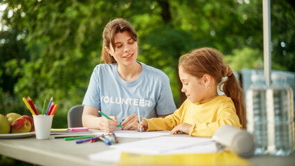 Volunteer from a Local Humanitarian Aid Organization Teaching a Talented Little Girl to Draw with Colorful Crayons. Happy Child and Charity Worker Having Fun Outdoors in Kindergarten.