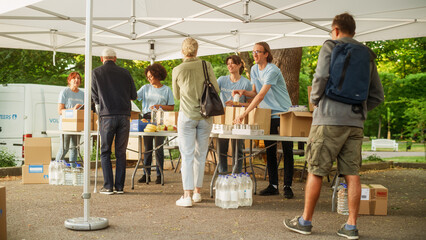 The Concept of Giving: Unemployed People Reach Out To Free Meals from Multiethnic Team of Volunteers. Humanitarian Aid Charity Workers Serve Meals to People in Need