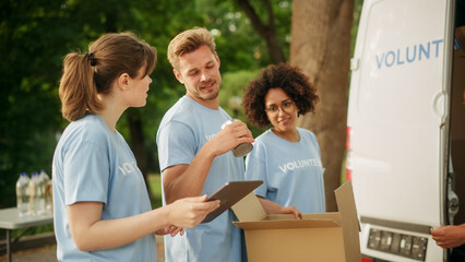 Happy Team of Young Volunteers Preparing Humanitarian Aid Rations, Food, Donations and Loading Cardboard Boxes in a Van on a Sunny Day. Charity Workers Work in Humanitarian Donation Center.