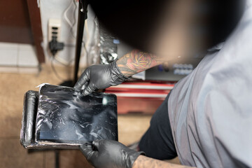 A tattoo artist is setting his work tablet station before tattooing