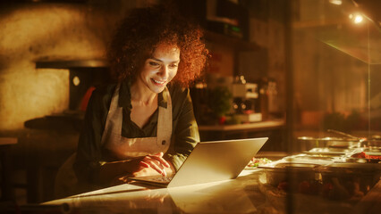 In Restaurant: Beautiful Female Chef Using Laptop Computer. Authentic Pizzeria With Delicious Organic Eco Food. Bi-racial Female Entrepreneur Working in Her Small Business Family Shop