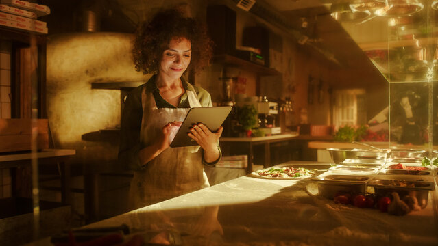 In Restaurant: Beautiful Female Chef Using Laptop Computer. Authentic Pizza Place Cooking Delicious Organic Eco Food. Bi-racial Female Entrepreneur Working on Online Order Small Business Family Shop