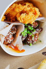 caramelized chicken with sesame and garlic, meat strips in paper bucket 