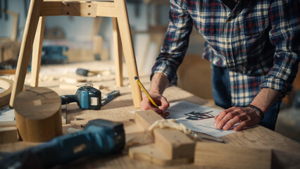 Young Woodworker Checking the Layout Manual of a Stylish Handmade Wooden Chair. Talented Furniture Designer Working in a Workshop in a Creative Loft Space with Tools and Equipment.