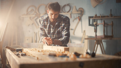 Young Artisan Craftsman in Checkered Shirt Using Hand Plane to Shape a Wood Bar. Handsome Carpenter...