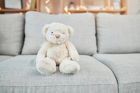 Teddy Bear, Child Toy And Baby Toys On A Living Room Sofa For A Christmas Or Birthday Present. Soft, Furry And Children Bear On A Home Lounge Couch With No People And Holiday Gift With Bokeh Lights