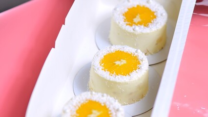 Small cakes with orange and coconut shavings in a box.