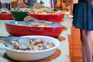 an unrecognizable person take sweets in a self service in a free buffet