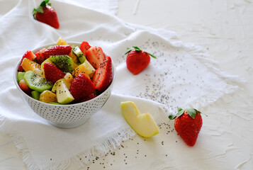 Bowl of healthy fresh fruit salad and chia seeds on a white napkin and white background. Low calories, healthy snack