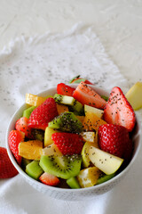 Bowl of healthy fresh fruit salad and chia seeds on a white napkin. Low calories, healthy snack