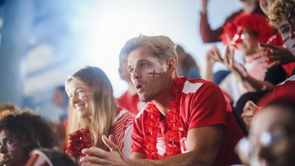 Sport Stadium Big Event: Handsome Man with Painted face Cheering. Crowd of Fans Shout for Red Soccer Team to Win. People on Tribune Celebrate Scoring a Goal, Championship Victory