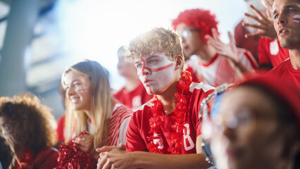 Sport Stadium Big Event: Handsome Man with Painted face Cheering. Crowd of Fans Shout for Red...
